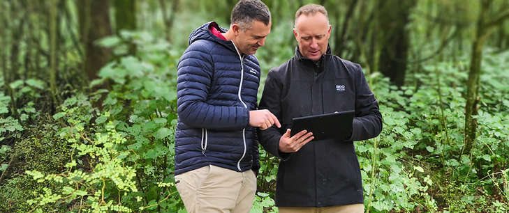 Two men in nature looking at a tablet device